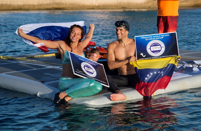 Carlos Coste & Marina Kazankova in the water showing certificates